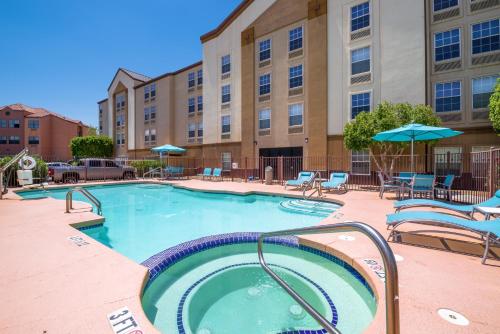 凤凰城Holiday Inn Express Phoenix-Airport/University Drive, an IHG Hotel的一座带椅子和遮阳伞的游泳池