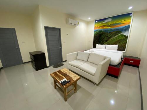 北碧Checkinn Resort Kanchanaburi的酒店客房配有床、沙发和桌子。