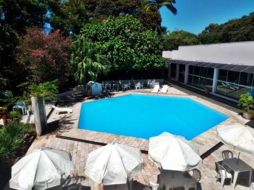 伊瓜苏阿尔沃拉达伊瓜苏酒店的一个带遮阳伞和椅子的大型蓝色游泳池