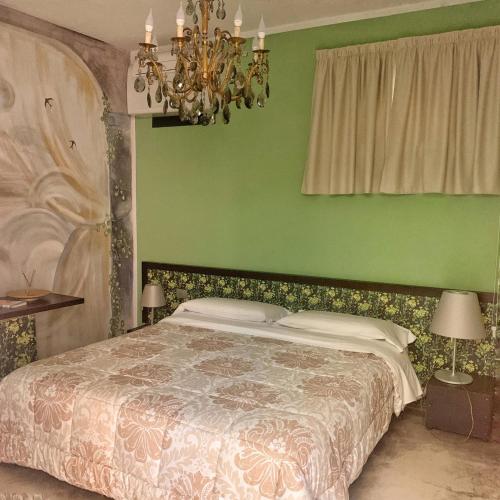 阿尔巴洛卡达特洛奥巴旅馆的绿色卧室配有一张床和吊灯