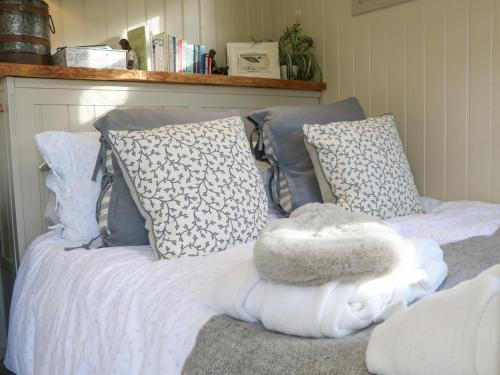 Preston CandoverGibson's Hut的一张带蓝色和白色枕头的床和白色毯子