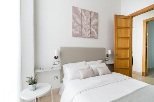 塞维利亚2E Stylish Bright Apartment Sevilla Downtown Azofaifo的白色卧室配有床和桌子
