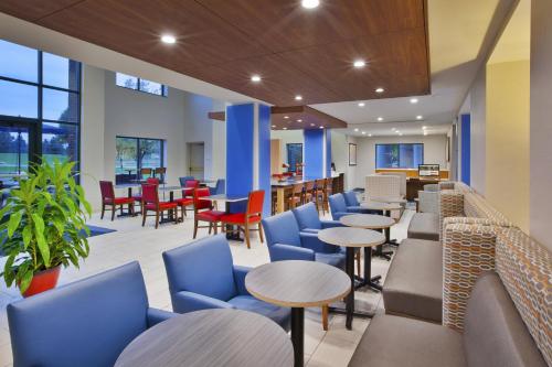 维克托快捷假日酒店罗切斯特 - 维克多的一间设有蓝色椅子和桌椅的餐厅