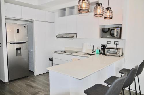 危地马拉Cozy Stays Cayala Apartments 3的白色的厨房配有白色的柜台和椅子