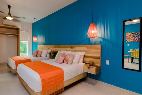 萨尤利塔Riviera Sayulita Hotel的一间卧室设有两张床和蓝色的墙壁