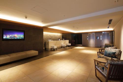 札幌MYSTAYS 札幌薄野酒店的大堂配有沙发和墙上的电视