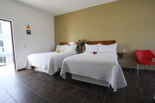 巴拉德纳维达Hotel Del Mar的一间卧室配有两张床、白色床单和红色椅子