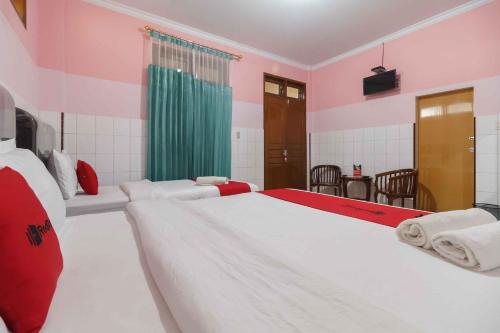 SunggalRedDoorz Plus @ Jalan Gatot Subroto Medan的一间卧室配有两张红色和白色的床