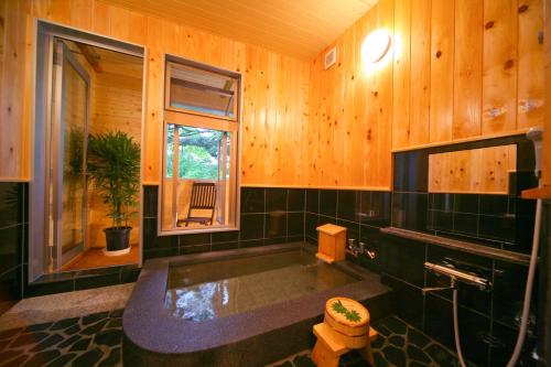日光Chuzenji Pension的一间带浴缸的浴室,位于一个窗口的房间