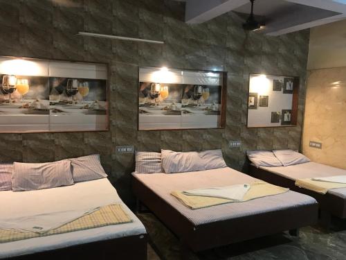 根尼亚古马里河伯酒店的带三张床和照片的墙壁的房间