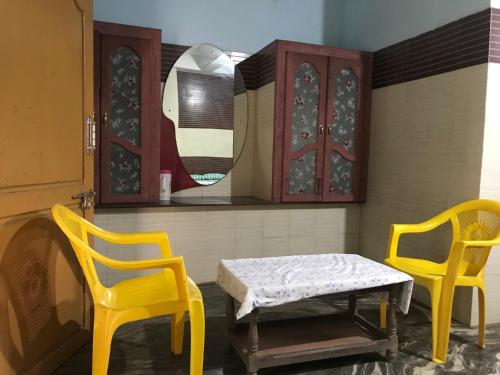 根尼亚古马里河伯酒店的两张黄色椅子、一张桌子和一面镜子