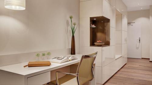 慕尼黑Boutique Hotel Atrium München的白色的厨房,配有书桌和花瓶
