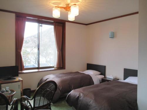 日光Chuzenji Pension的酒店客房设有两张床和窗户。