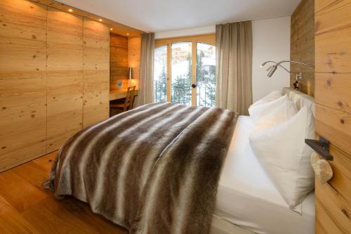 采尔马特哈罗公寓酒店的一间卧室配有一张床铺,床上有毯子