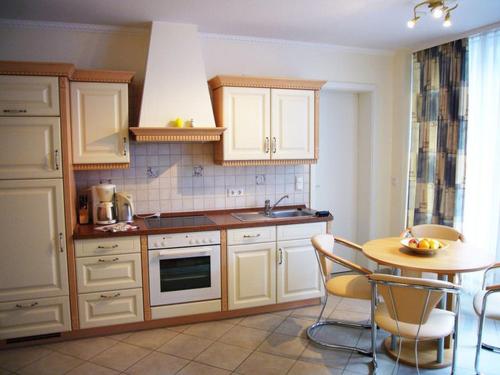 诺伊霍夫Villa Seestern _ Wohnung 2的厨房配有白色橱柜和桌椅