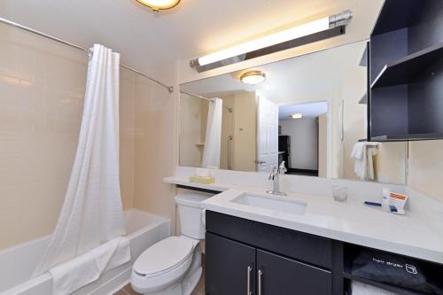 Sayre塞尔坎德尔伍德套房酒店的浴室配有盥洗盆、卫生间和浴缸。