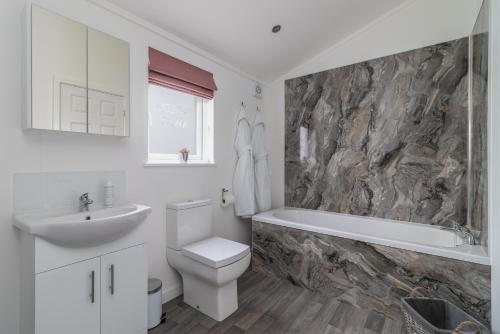 HuggateWolds Away的浴室配有盥洗盆、卫生间和浴缸。