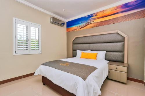 德班African Sun lodge的卧室配有一张床,墙上挂有绘画作品