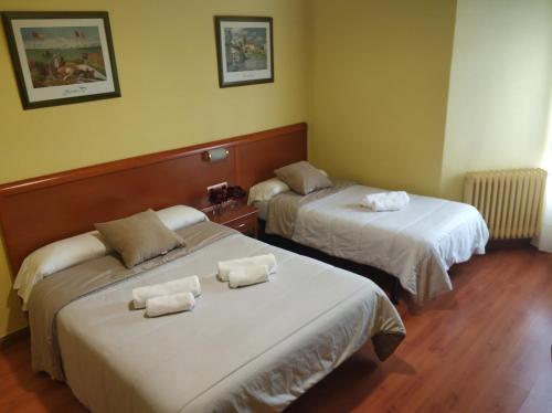 布尔戈斯Hostal Restaurante Iruñako的两张位于酒店客房的床,配有毛巾