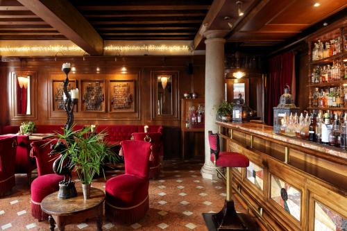 威尼斯Hotel Metropole Venezia的餐厅设有酒吧,配有红色椅子和柜台