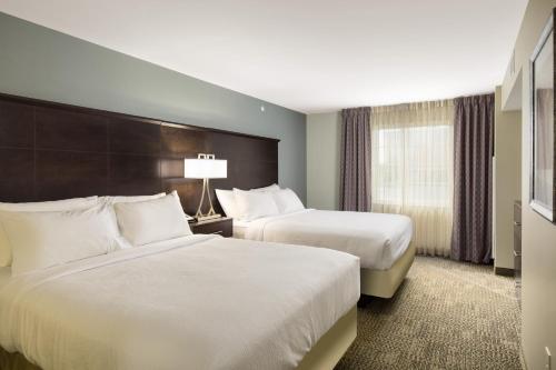 莫米Staybridge Suites Toledo/Maumee, an IHG Hotel的酒店客房设有两张床和窗户。