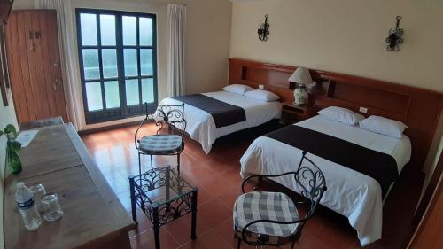 Texcoco de MoraHotel Posada Santa Bertha的酒店客房设有两张床和一张桌子。