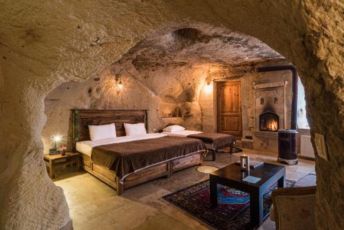 内夫谢希尔Atilla's Cave Hotel的洞穴内的卧室配有床和壁炉