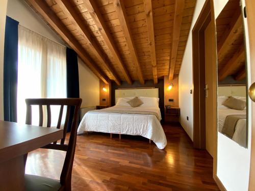 CaprioloSole della Franciacorta - Hotel & Restaurant的一间卧室配有两张床、一张桌子和一张书桌