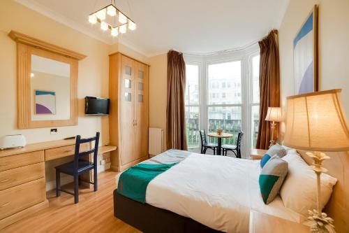 布莱顿霍夫The Gullivers Hotel的配有一张床、一张书桌和一扇窗户的酒店客房