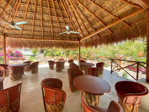 坎昆MIO Cancún Hotel Boutique的茅草屋顶下设有桌椅的餐厅