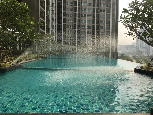 曼谷Supalai Rama9 Monthly的一座建筑中间的游泳池,有一个喷泉
