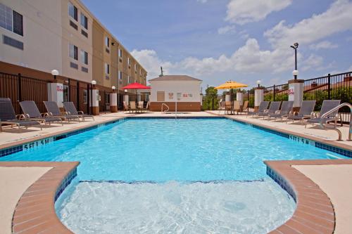 休斯顿Candlewood Suites Houston Westchase - Westheimer, an IHG Hotel的一座带椅子的酒店游泳池以及一座建筑