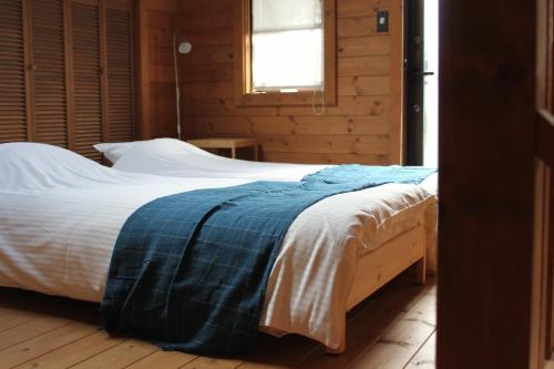 白马村白马高山度假屋的一间卧室配有一张带蓝色毯子的床