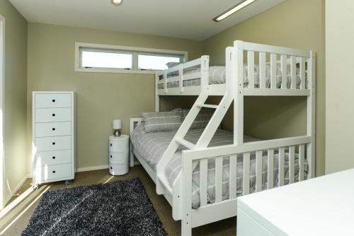 WaimaramaWaimarama Wonder - Waimarama Holiday Home的卧室配有带梯子的白色双层床