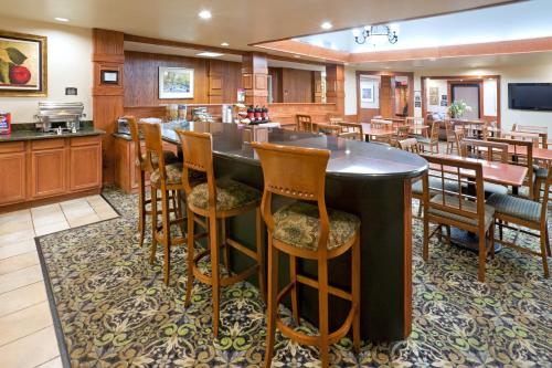 拉伯克Staybridge Suites Lubbock-University Area, an IHG Hotel的一个带酒吧的大厨房,酒吧配有木椅