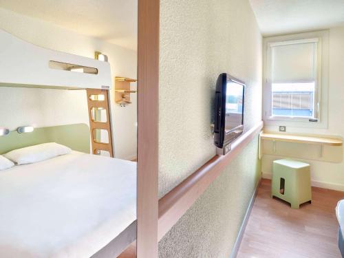 圣保罗莱达圣保罗-莱达宜必思快捷酒店的一间卧室配有一张床,并在一间客房内配有电视。