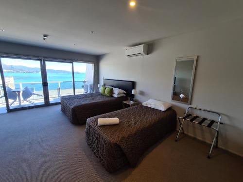 Te KahaTe Kaha Beach Hotel的酒店客房设有两张床和一个阳台。