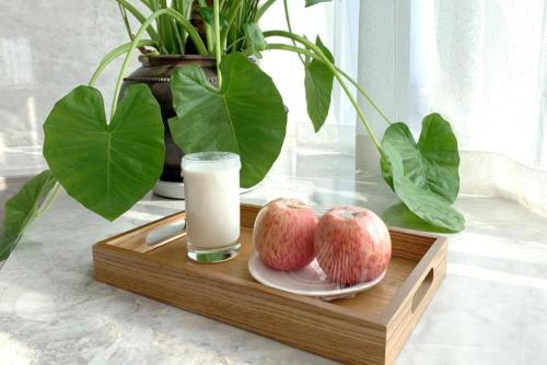 重庆重庆白云亲舍精品酒店的装有两只苹果和一杯牛奶的木托盘