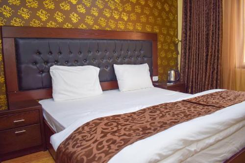 亚喀巴Hotel Prestige的一间卧室配有一张大床和木制床头板