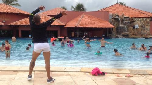 福塔莱萨Aquaville Resort的站在游泳池中的女人,手臂挺起来