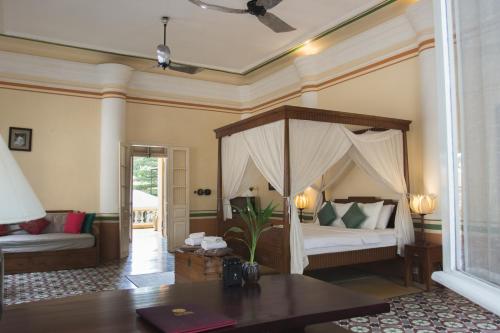 马德望拉维拉酒店的一间卧室配有一张天蓬床和一张桌子