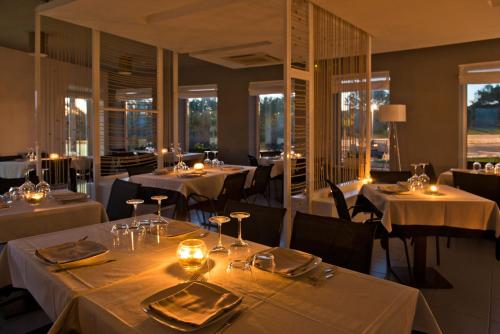 塔兰托Mon Rêve Resort的餐厅设有白色的桌椅和窗户。