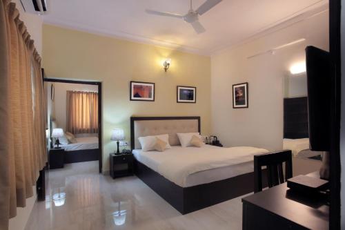 乌代浦Mimosa Udaipur的一间卧室配有两张床和电视。