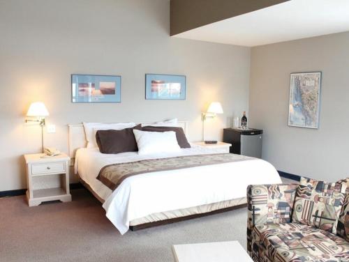 哈迪港Quarterdeck Inn Port Hardy的卧室配有一张白色的大床和一张沙发。
