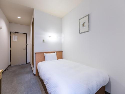 伊势崎市Hotel Isesaki East的一间小卧室,配有白色的床和一扇门