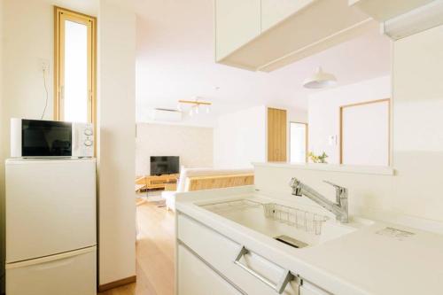 东京Akiba Residence的白色的厨房配有冰箱和水槽