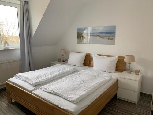奥斯赛拜-屈隆斯博恩Appartementhaus Ulmenhof的一间卧室配有一张带白色床单的床和一扇窗户。