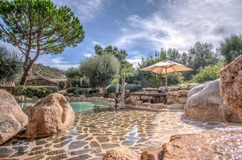 维琪奥港Villa Serenita Pallombaggia的一个带遮阳伞和岩石的游泳池
