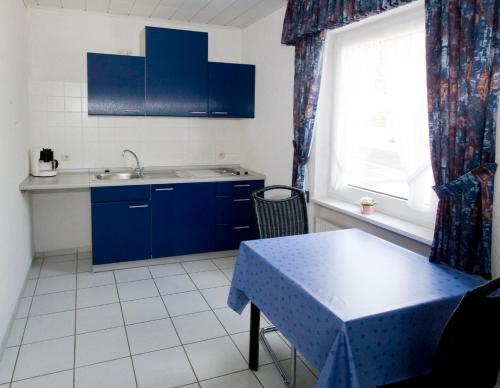 圣阿尔德贡德Pension Mosella , Wohnung mit Balkon und Moselblick的厨房配有蓝色橱柜、桌子和窗户。