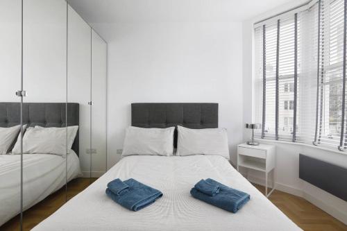 布莱顿霍夫Clarence Square的一间白色卧室,床上配有2条蓝色毛巾